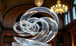 transparent acrylic sculpture, expressively artistic, twisting elegance, photorealistic, historical library interior, highly detailed, ricocheting light, full spectrum, sharp contrasts, classic chandelier lighting, shot with a portrait lens.